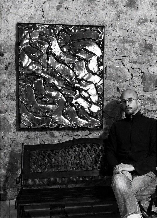 Vincent GILD seated in his Burgundy studio beside one of his works